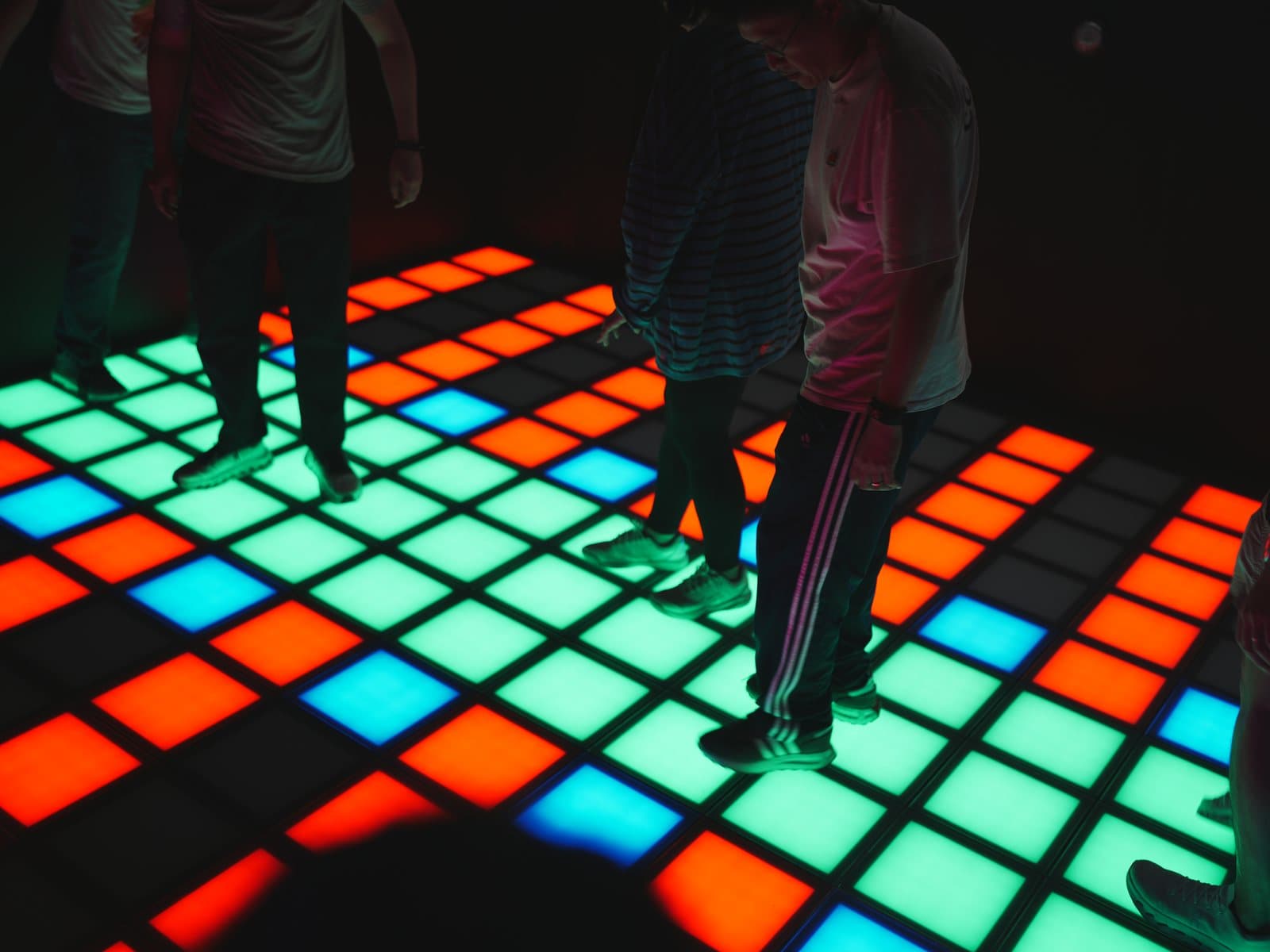 A group stepping across the colorful interactive Pixel floor at Simple Pixel